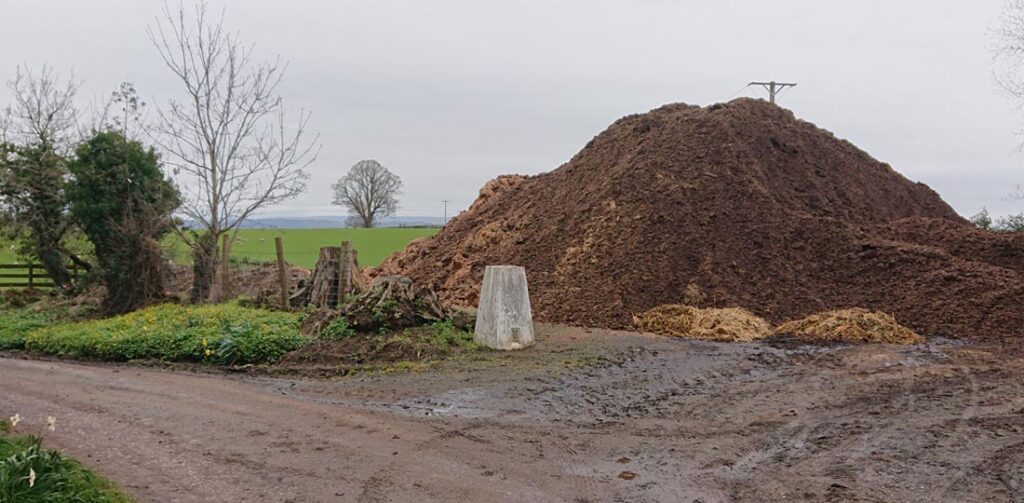 Trig pillar by a mound of dirt